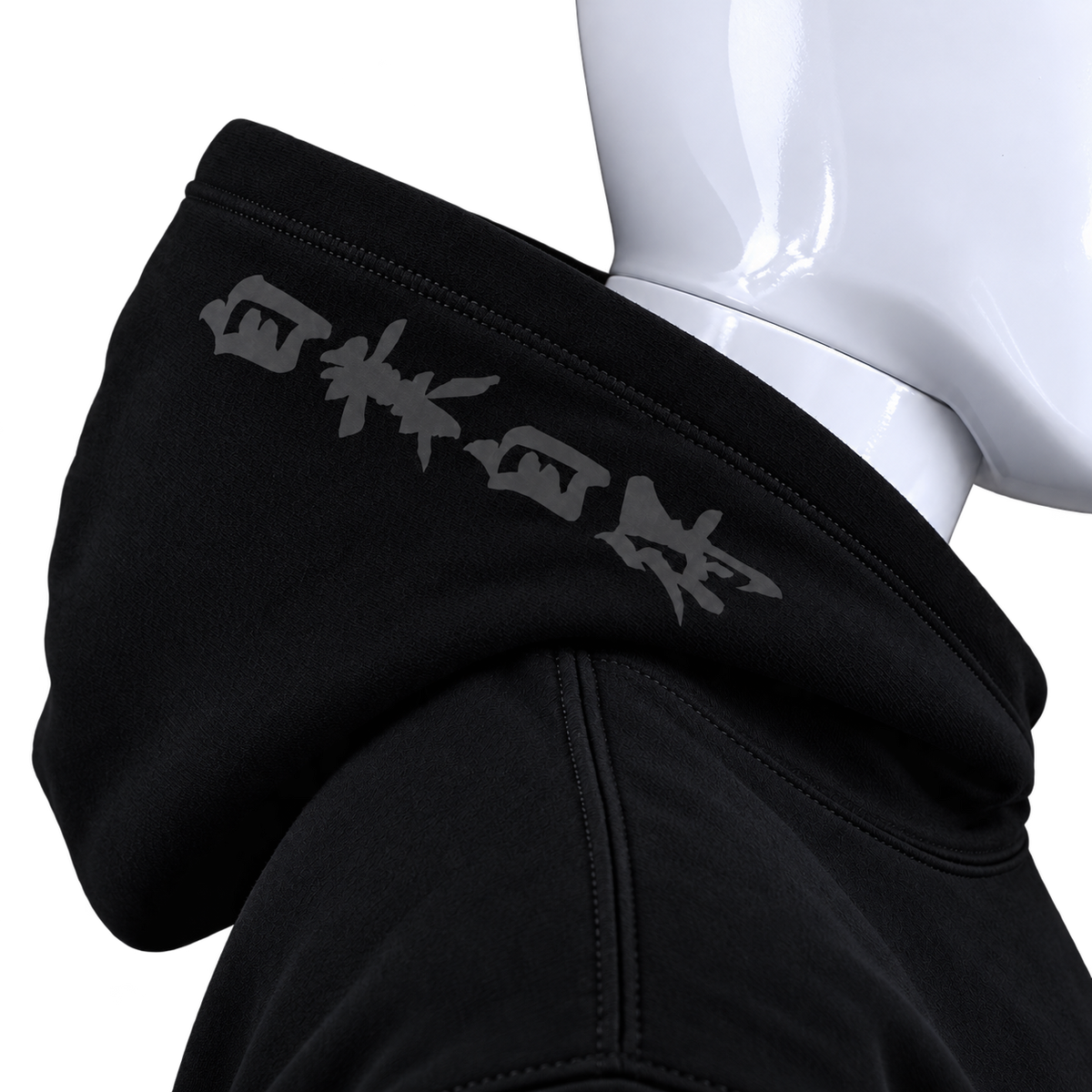 Close-up of a black hoodie on a white mannequin torso, showing the hood with gray stylized text across the collar.